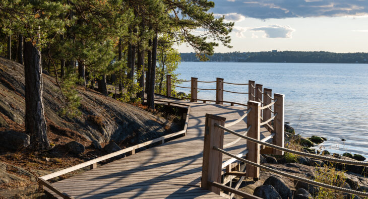 Bild på Artipelags strandpromenad i lärkträ i kvällssolen.