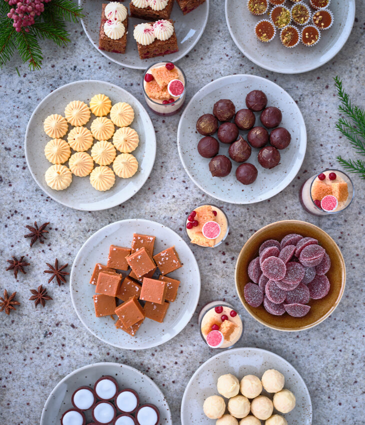 Bilden föreställer julgodis fotat ovanifrån, på bilden ser man tallrikar fyllda med fudge, knäck, mintkyssar och praliner.