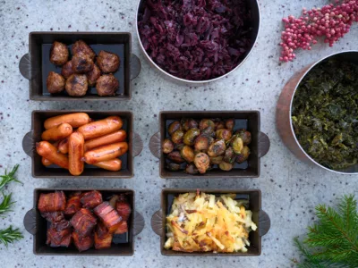 Bilden föreställer ett dukat julbord med varma rätter så som Janssons frestelse, rödkål, prinskorvar, köttbullar och revbensspjäll.