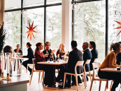 Människor som äter i en modern restaurang med stora fönster och dekorativa stjärnljus.